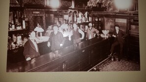 A vintage bar with ornate decor, including a patterned wallpaper and a ceiling with a decorative design.