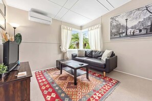 A living room with a sofa, coffee table, TV, and a patterned rug.