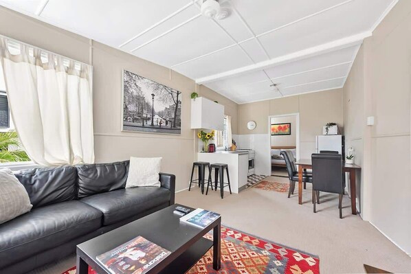 A modern living room with a sofa, coffee table, and a dining area with chairs and a table.