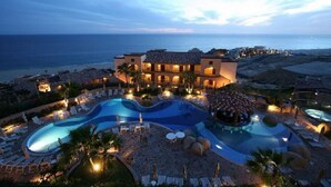 Un resort con varias piscinas, un edificio de varios pisos y vista al océano.