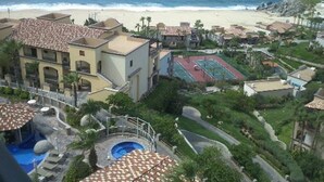 Un resort con piscina, cancha de tenis y vista a la playa.