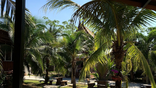A courtyard with palm trees, outdoor seating, and a clear blue sky. - Satun Boutique Resort (Satun)