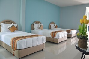 A hotel room with three beds, each with a headboard and pillows. There is a small table with a vase of flowers. - Satun Boutique Resort (Satun)