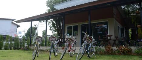 A building with a covered porch and several bicycles parked outside.