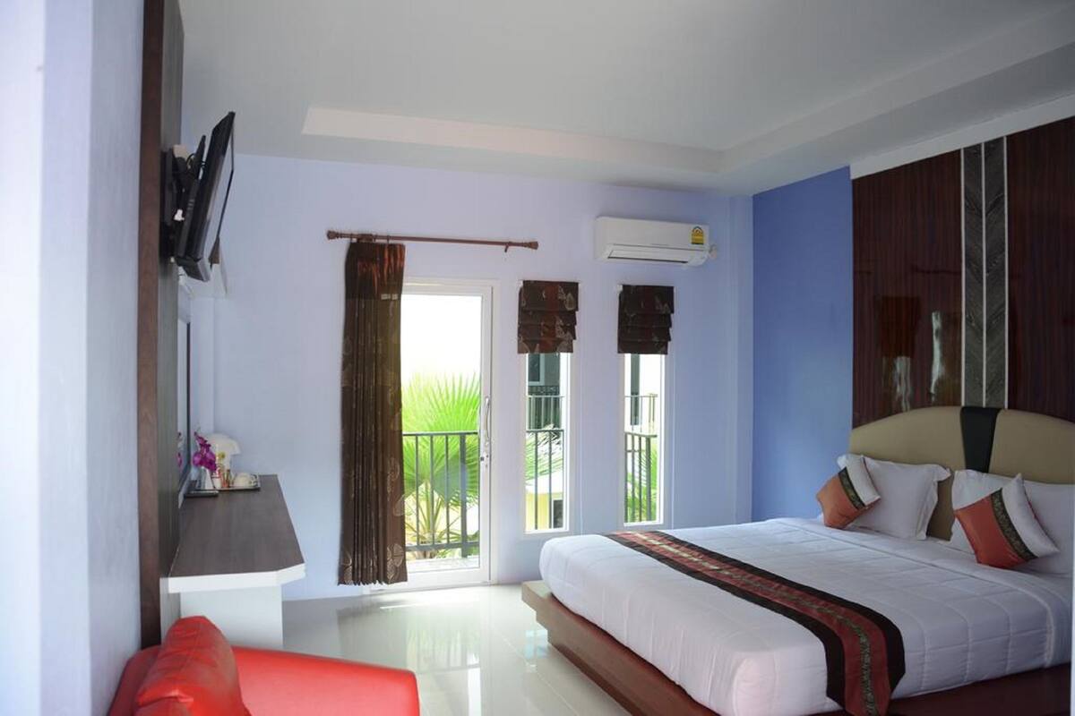 A hotel room with a bed, a desk, a chair, and a television.