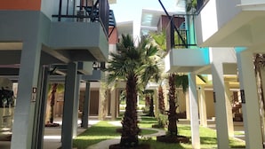 A multi-level atrium with a central garden area, featuring palm trees and a clear sky. - Satun Boutique Resort (Satun)