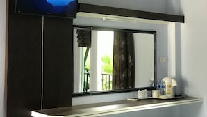 A hotel room with a flat-screen TV mounted above a mirror, a coffee maker, and a small table with toiletries. - Satun Boutique Resort (Satun)