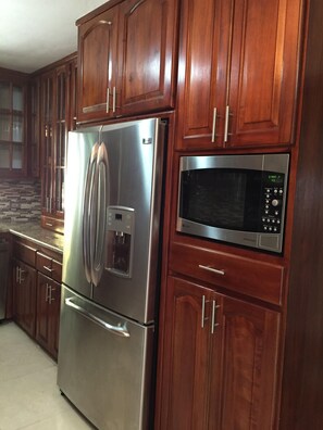 A kitchen with wooden cabinets, a stainless steel refrigerator, and a microwave.