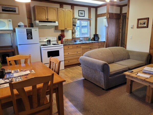 Une cuisine de taille réduite, dotée de meubles en bois, d’une cuisinière et d’un coin repas avec une table et des chaises.