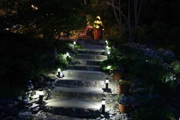 A stone staircase with multiple steps, flanked by potted plants and lit by small lanterns.