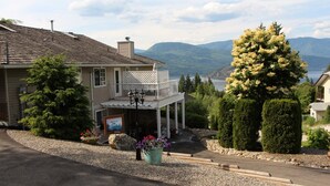 A two-story house with a balcony, surrounded by well-maintained landscaping and a view of a lake and mountains. - Selah Retreat Guesthouse B&B -  "Defining Tranquility, Beauty and Excellence!" (Sorrento)