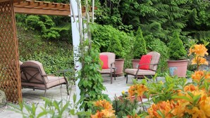 A covered outdoor seating area with chairs and a pergola, surrounded by lush greenery and flowering plants. - Selah Retreat Guesthouse B&B -  "Defining Tranquility, Beauty and Excellence!" (Sorrento)