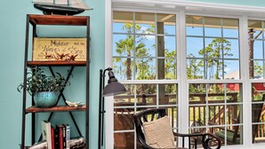Eine gemütliche Leseecke mit einem Sessel, einem Bücherregal und einem Fenster mit Blick ins Freie.