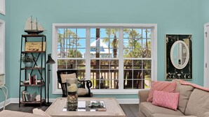 Ein gemütliches Wohnzimmer mit großem Fenster, einer Bücherwand und einer bequemen Couch.