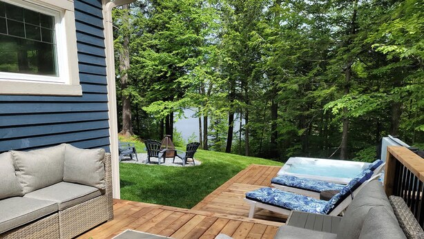 A deck with outdoor furniture, a hot tub, and a lawn.