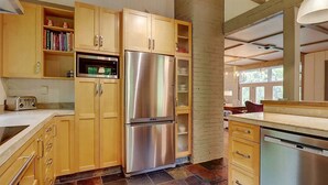 A kitchen with wooden cabinets, a stainless steel refrigerator, a built-in oven, and a dishwasher.