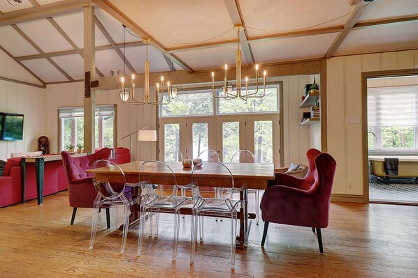 A dining area with a wooden table, clear chairs, and a chandelier.