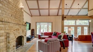 A spacious living room with a stone fireplace, a red sofa, and a striped armchair.
