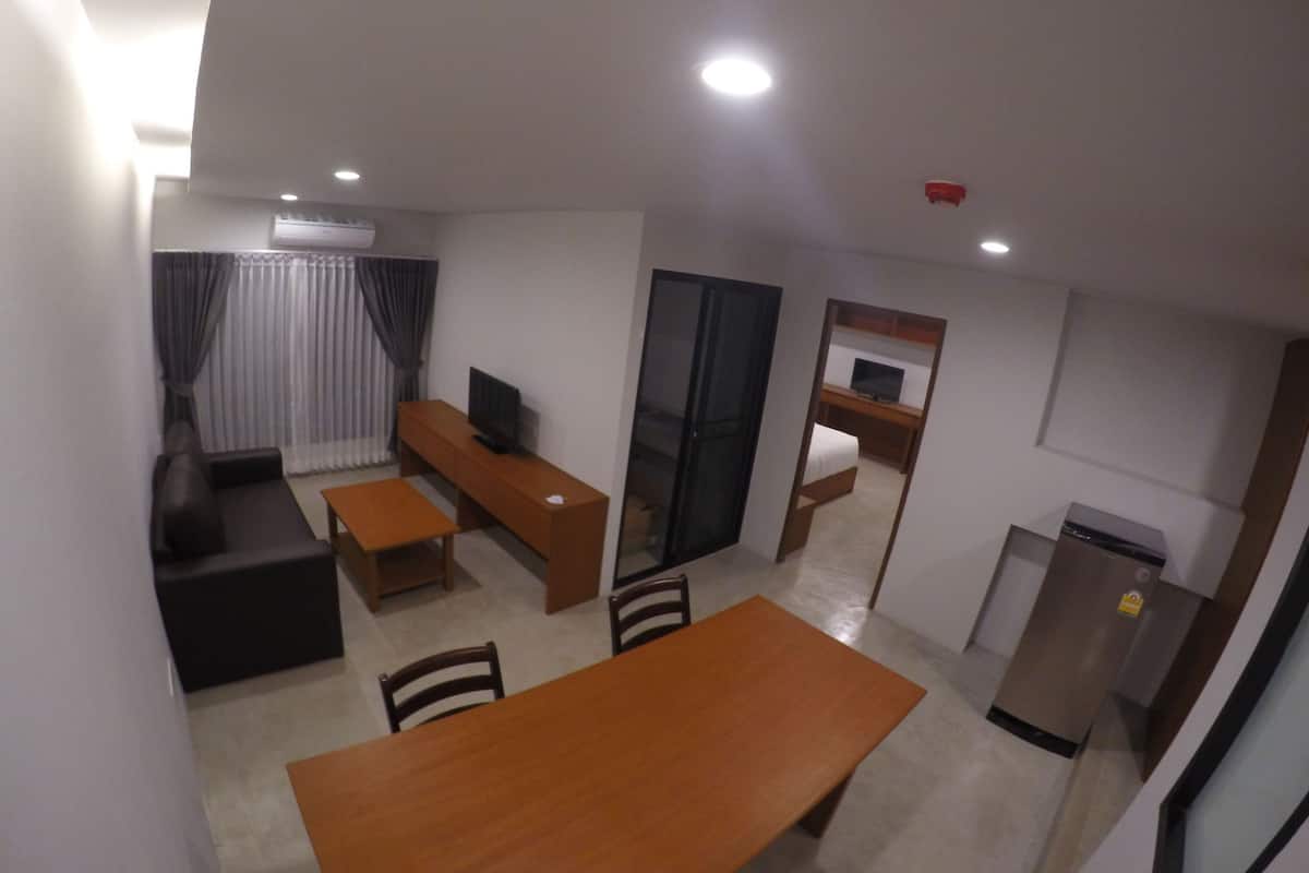 A compact living space with a dining table, a sofa, a TV, and a kitchenette.