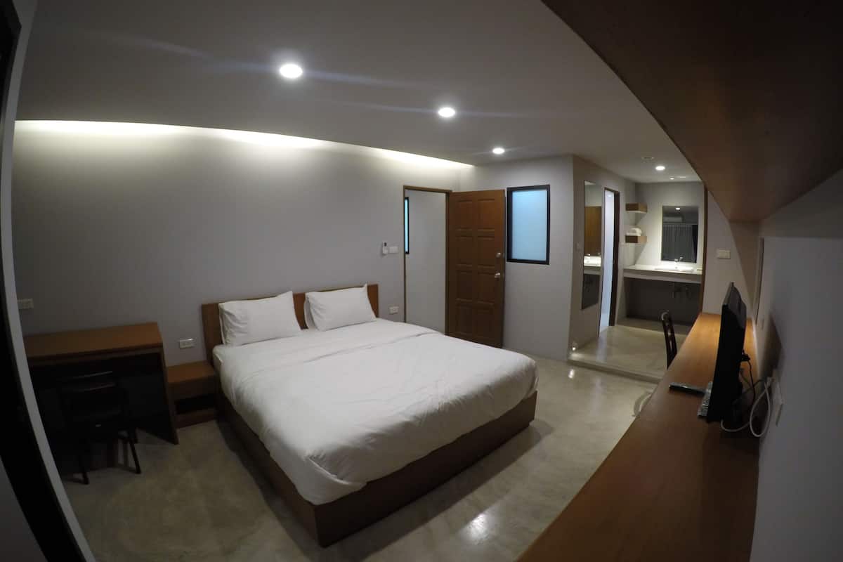 A modern bedroom with a large bed, a desk, and a mirror.