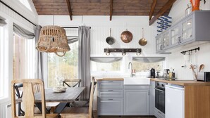 Une cuisine avec une table et des chaises de salle à manger en bois, des armoires blanches et un luminaire suspendu.