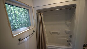 Un baño con bañera, ventana y cortina de ducha.