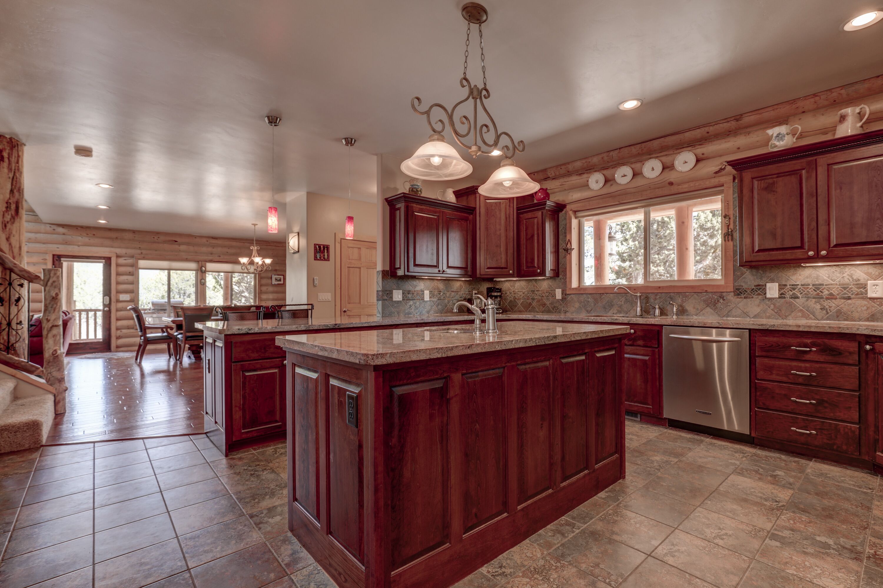 A spacious kitchen with dark wood cabinets, a large island, and a stainless steel dishwasher.