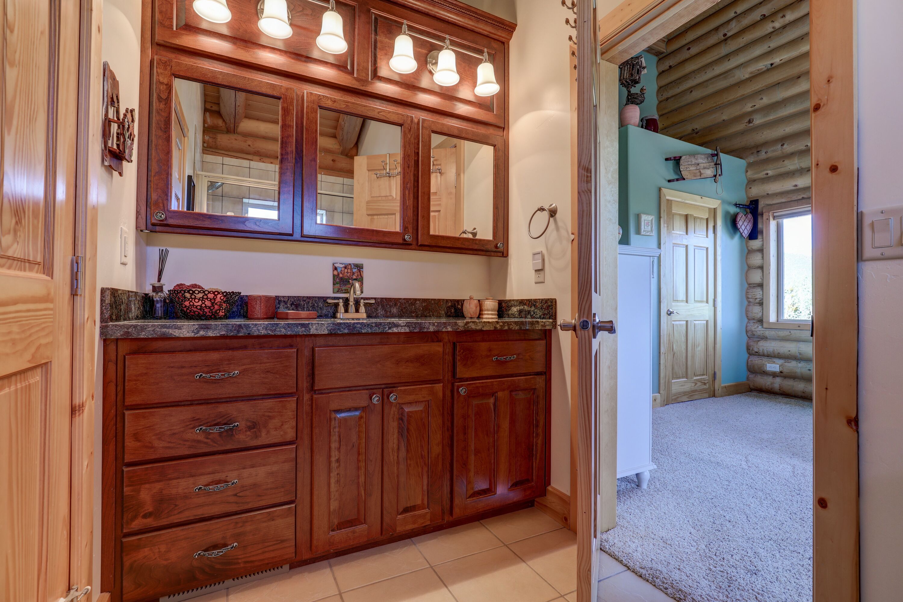 A wooden bathroom vanity with a large mirror and multiple lights.