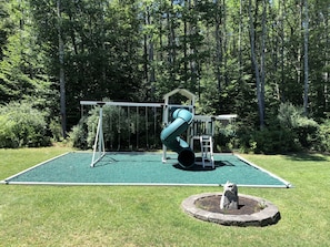 Children can play on the swing set and slide in this well-maintained playground area surrounded by trees.