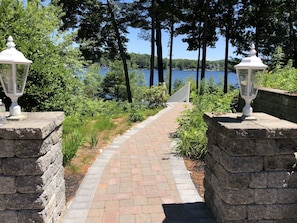 Stroll along the serene pathway to a tranquil oasis surrounded by lush greenery and a peaceful body of water.