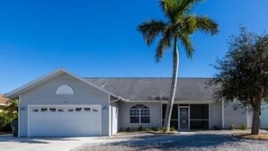 A single-story house with a garage, a small porch, and a palm tree in the front yard.