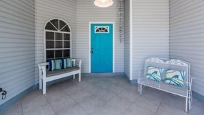 A hallway with a blue door, a white bench, and a white bench with patterned cushions.