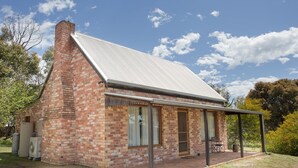 A brick house with a metal roof, a porch, and a small garden area.