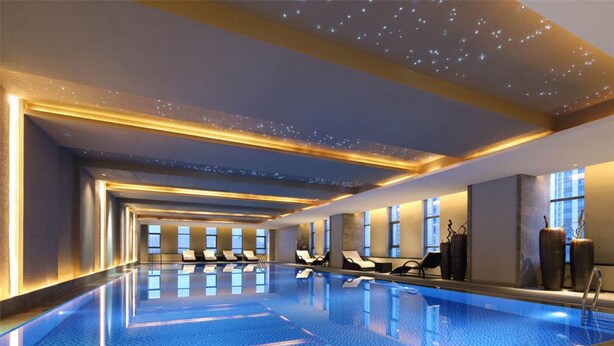 Ein modernes Hallenbad mit länglichem Grundriss, Liegestühlen entlang der Seiten und einer Decke mit sternförmigen Lichtern.