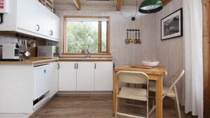 A compact kitchen with white cabinets, a wooden countertop, a window, and a table with a chair. - Múlakot 5 - Cosy cabin, View the amazing view´s from the porch (Borgarbyggð)