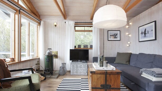A cozy living room with a sofa, a wooden coffee table, a television, and a large window with curtains. - Múlakot 5 - Cosy cabin, View the amazing view´s from the porch (Borgarbyggð)