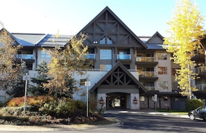 Stunning building with a triangular gable roof and arched entrance, set amidst lush autumn surroundings.