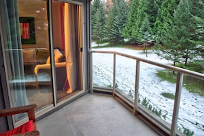 Enjoy breathtaking views of the snowy landscape from this room's balcony, featuring a glass door and a comfortable bed.