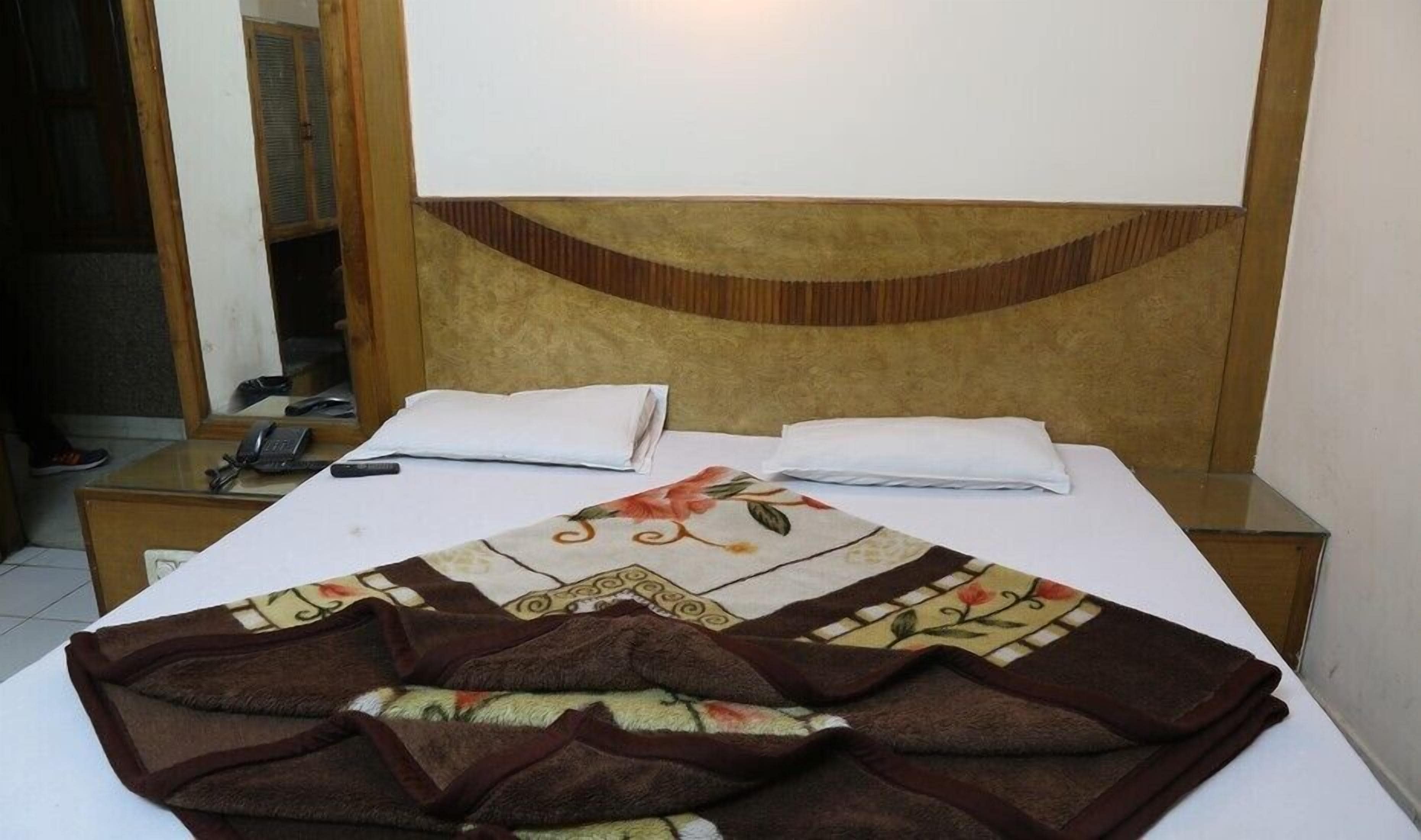 Ein Hotelzimmer mit einem Bett, zwei Nachttischen, einem Telefon und einem Spiegel.