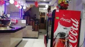 A reception area with a Coca-Cola vending machine, a reception desk, and a staircase leading to another floor. - Hotel Delhi Regency (New Delhi)