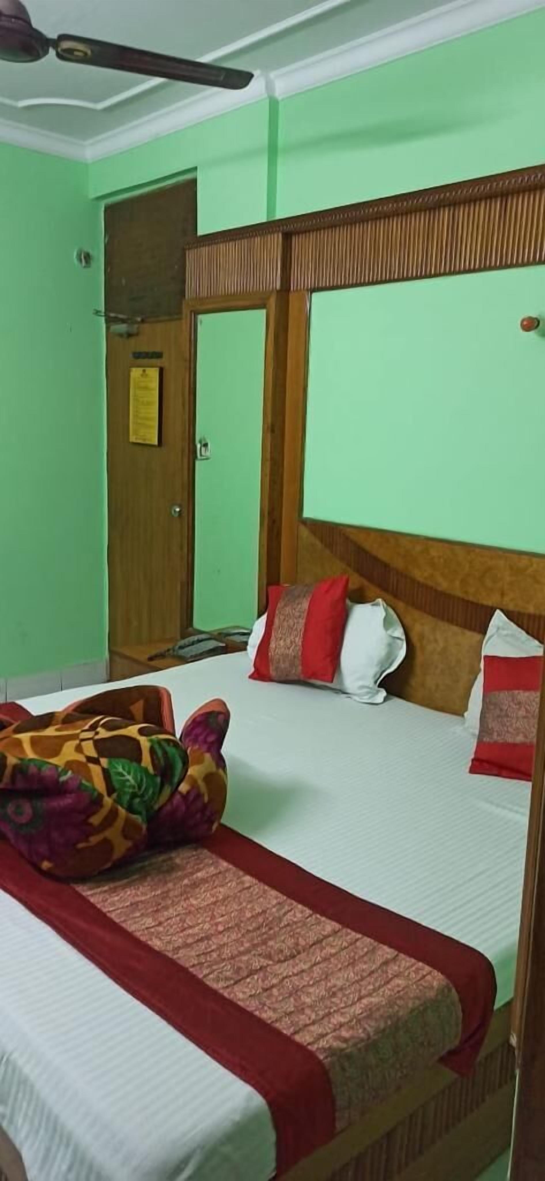 Una habitación con cama, cabecera de madera, una puerta con un letrero y un ventilador de techo.
