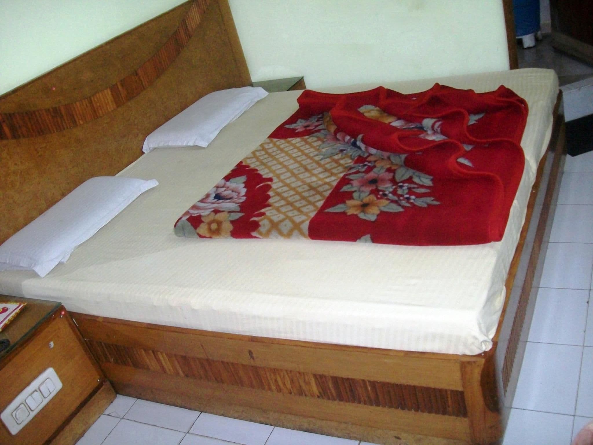 A bed with a wooden headboard, white pillows, and a floral blanket.