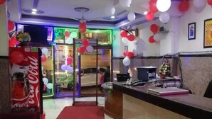 A reception area with a counter, seating, and a Coca-Cola refrigerator. - Hotel Delhi Regency (New Delhi)