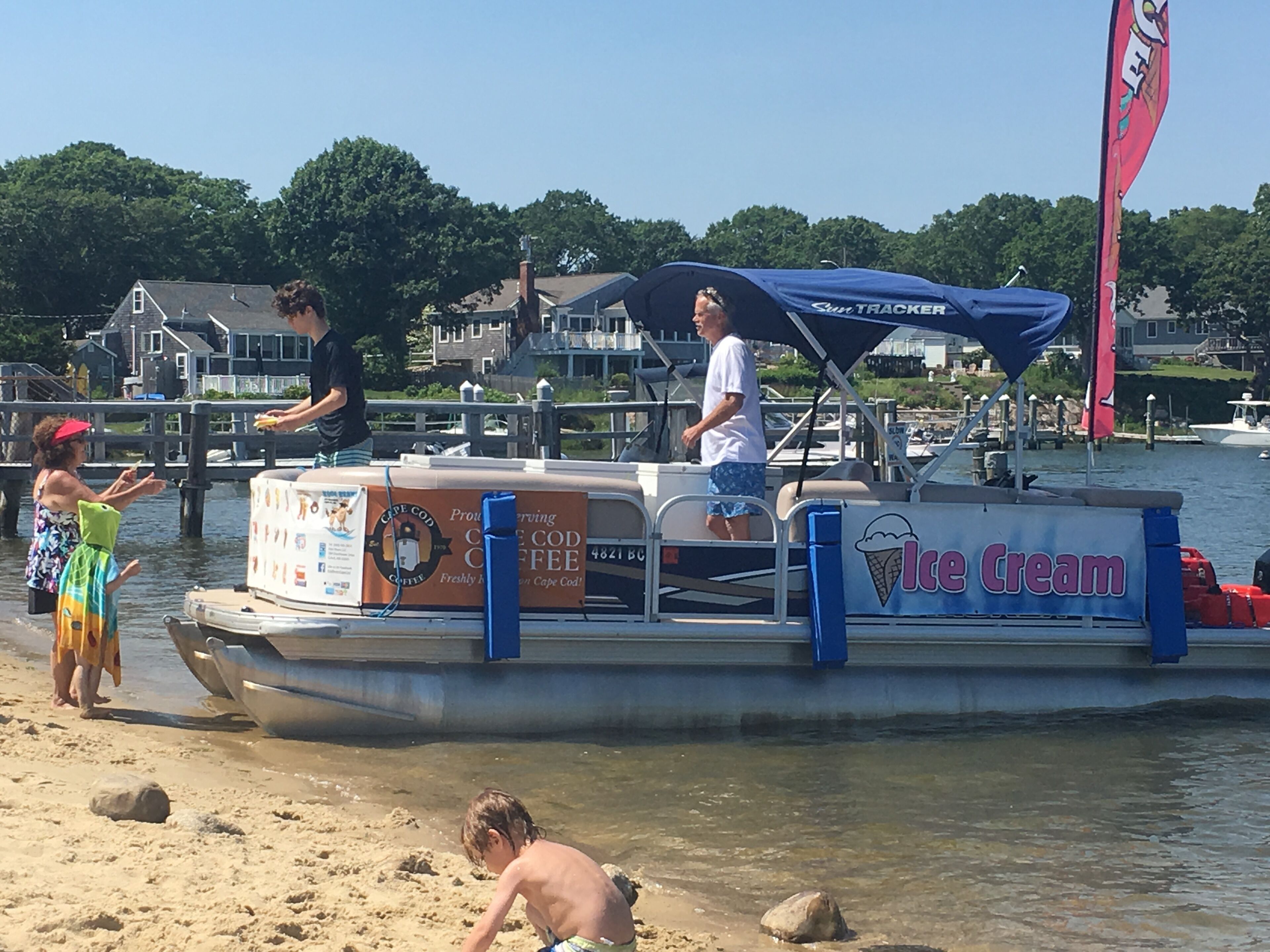 Un bateau arborant une publicité pour des glaces, et une personne se tenant sur le quai.