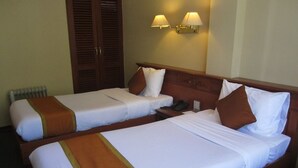 A hotel room with two single beds, a wooden headboard, a bedside table with a phone, and two wall-mounted lamps. - Hotel Jumolhari (Thimphu)