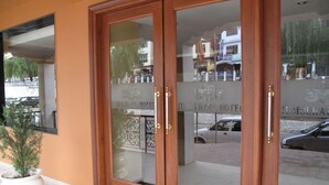 A hotel entrance with a wooden door and glass panels, a potted plant, and a tiled floor. - Hotel Jumolhari (Thimphu)