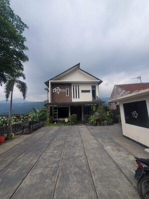 A two-story house with a covered patio area, a visible garage, and a mountain view in the background.