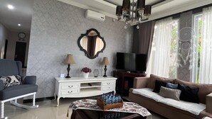 Una sala de estar moderna con sofá, una mesa de centro, televisor y un espejo decorativo.