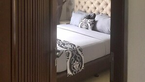 Un dormitorio con cabecera capitonada, cama con ropa de cama estampada y puerta con el número 202.