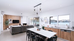 A modern kitchen with a dining area, large windows, and a view of the sea. - Beach front apartment with swimming pool ideal for families (Ligaria Beach)
